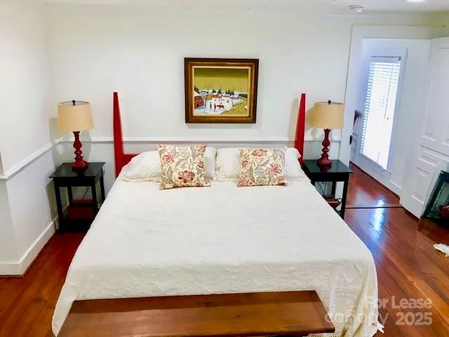 a large bed sitting in a bedroom next to a window with wooden floor