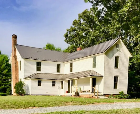 a view of a white house with large windows and a big yard with plants