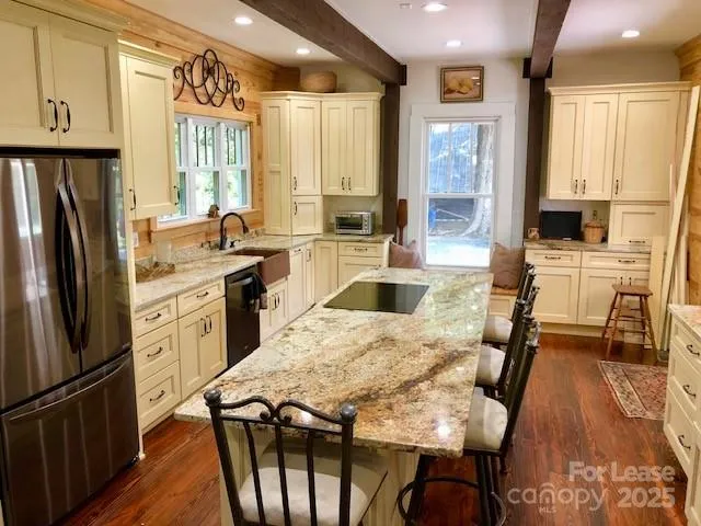 a kitchen with stainless steel appliances granite countertop a refrigerator a stove a sink dishwasher and white cabinets with wooden floor
