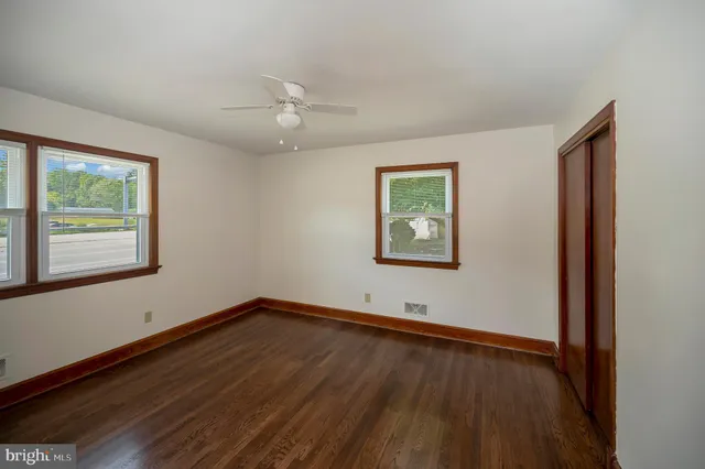 a view of empty room with wooden floor and fan