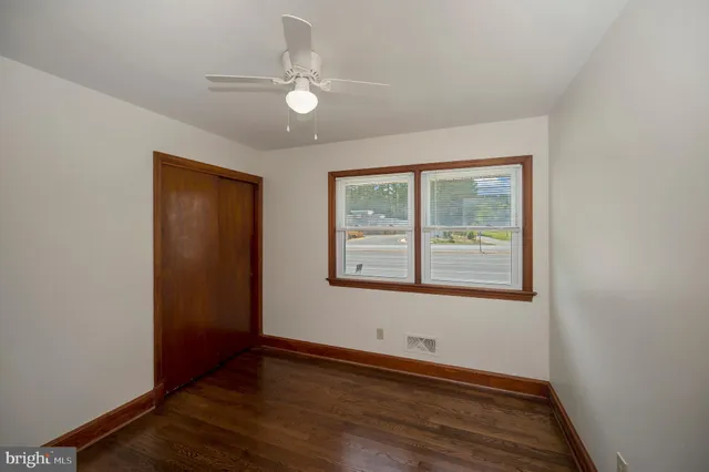 an empty room with wooden floor cabinet and windows
