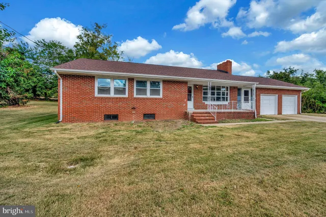 a front view of house with yard and trees in the background