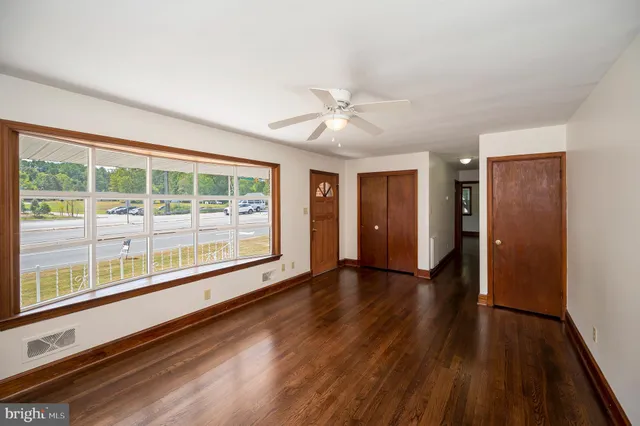 a view of an empty room with a window and wooden floor