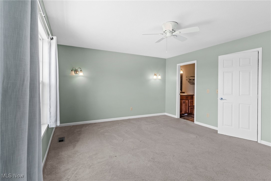 5215 River Road Madison, OH 44057 - Photo 15 of 36 Unfurnished bedroom featuring carpet floors, connected bathroom, and ceiling fan