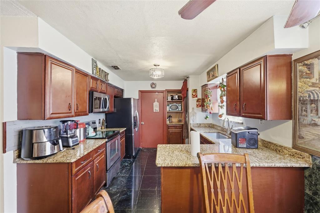 3027 Queens Gate Road Orlando, FL 32818 - Photo 16 of 34 a kitchen with stainless steel appliances granite countertop a sink stove and refrigerator