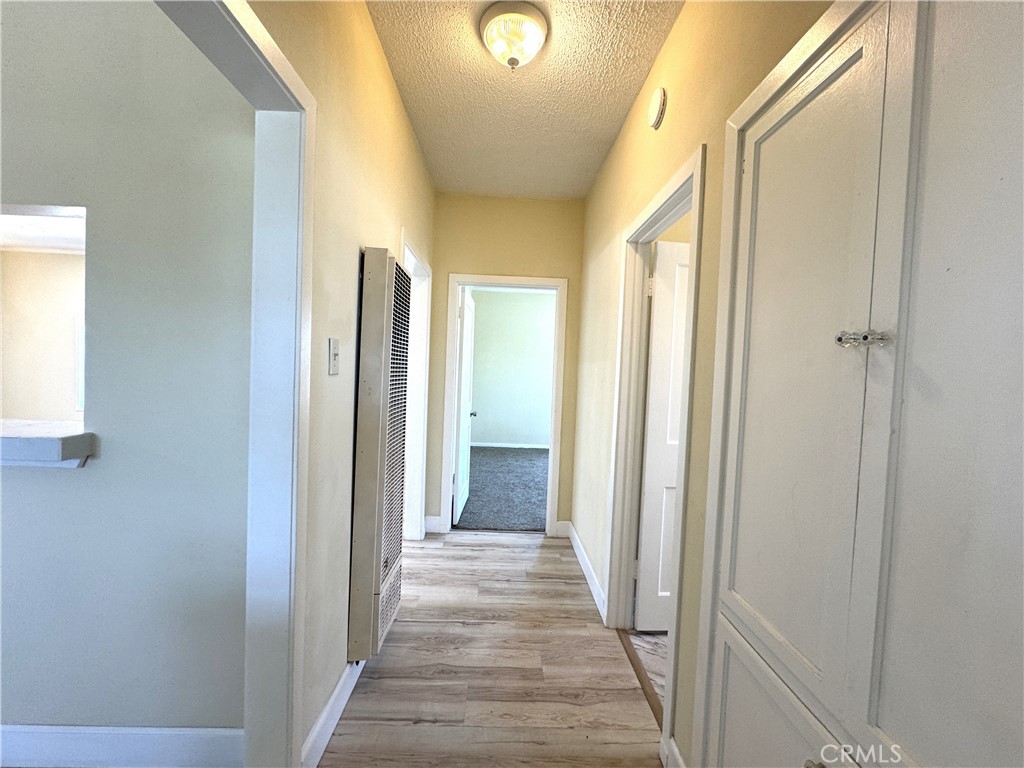 13407 Holly Street Trona, CA 93562 - Photo 11 of 25 Hallway
Wide hallway with fresh flooring and built-in cabinetry providing extra storage and organization. Neutral paint and updated lighting keep the space bright and welcoming. Convenient central layout offers easy access to bedrooms and living areas. Open cut-out from the hall to the kitchen brings added light and flow.