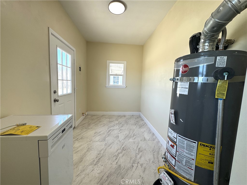 13407 Holly Street Trona, CA 93562 - Photo 14 of 25 Utility / Laundry Room – 13407 Holly
Spacious utility room with durable tile flooring and plenty of room for washer/dryer setup.
Features an updated Rheem water heater and exterior access for added convenience.
Window and back door allow in natural light, keeping the space bright and functional.
Ideal for laundry, storage, or even a mudroom — a versatile bonus to the home.