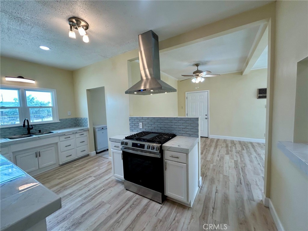 13407 Holly Street Trona, CA 93562 - Photo 3 of 25 Kitchen
Fully updated kitchen featuring sleek countertops and stylish subway tile backsplash.
Stainless steel range with a statement hood vent as the focal point.
Abundant cabinet space with modern hardware and a smart layout for functionality.
Pass-through window to the living space adds charm and convenience.