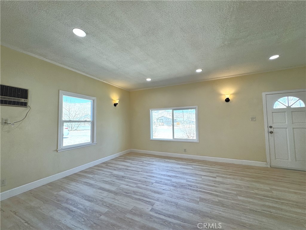 13407 Holly Street Trona, CA 93562 - Photo 7 of 25 Living Room – 13407 Holly
Bright and open living room featuring new wood-look flooring and fresh neutral paint for a modern, move-in ready feel.
Large dual-pane windows flood the space with natural light while offering desert and mountain views.
Recessed lighting paired with stylish wall sconces creates a warm, inviting ambiance day or night.
Classic front door design adds character, while the open layout flows seamlessly into dining and kitchen areas.
Comfortable and versatile, this livin...