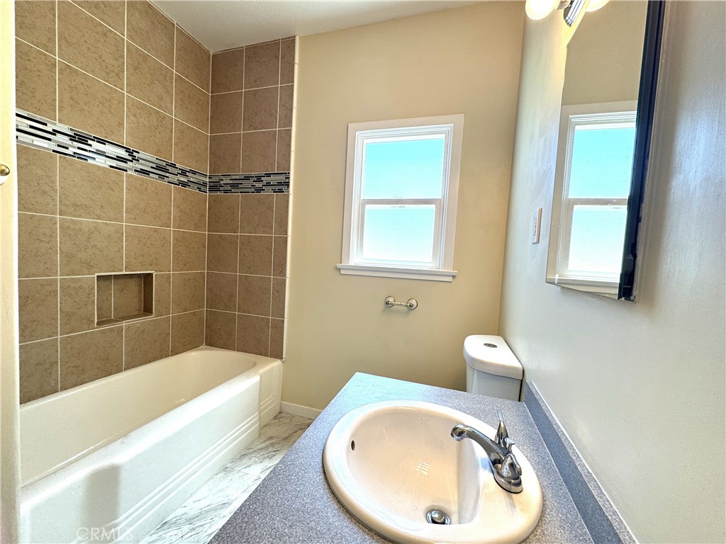 13407 Holly Street Trona, CA 93562 - Photo 8 of 25 Bathroom – 13407 Holly
Freshly updated bathroom with a modern tiled tub/shower surround featuring a decorative accent strip and built-in niche.
Spacious vanity with extended counter space and under-sink storage.
Dual-pane window brings in natural light while maintaining privacy.
Neutral tones and clean finishes create a bright, inviting space ready for everyday use.