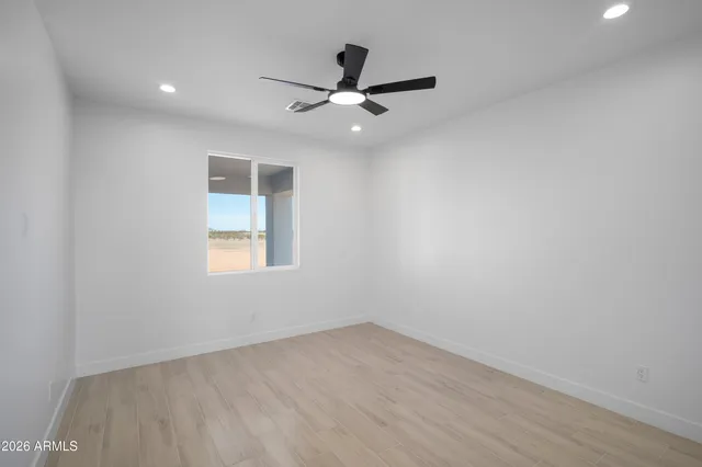 an empty room with wooden floor ceiling fan and windows