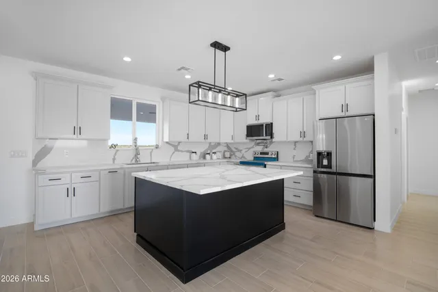 a kitchen with kitchen island granite countertop a sink cabinets and stainless steel appliances