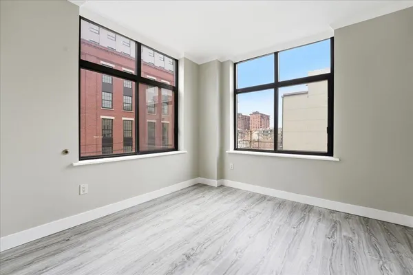 an empty room with wooden floor and windows