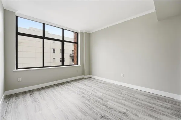 an empty room with wooden floor and windows