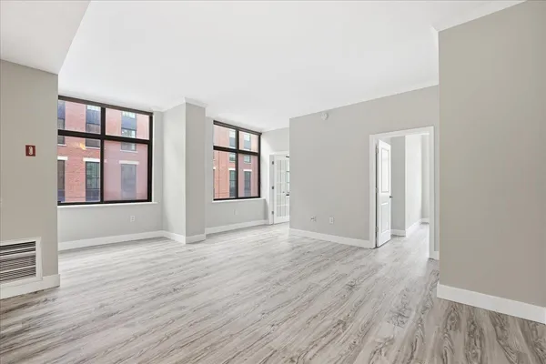 an empty room with wooden floor and windows