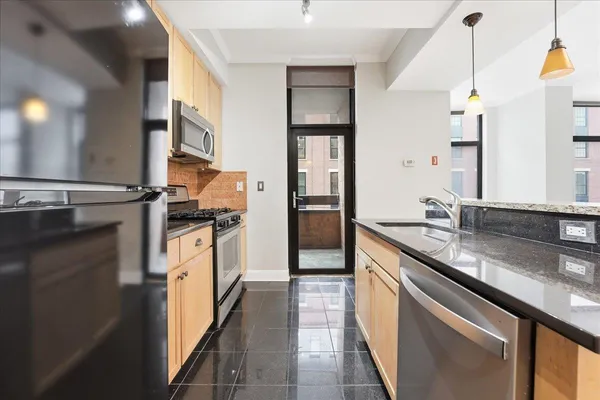 a kitchen with stainless steel appliances granite countertop a sink and a refrigerator