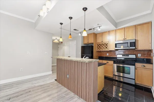 a kitchen with stainless steel appliances granite countertop a sink a stove and a wooden floors
