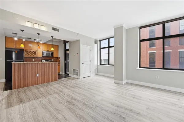 a view of a kitchen with an empty room and wooden floor