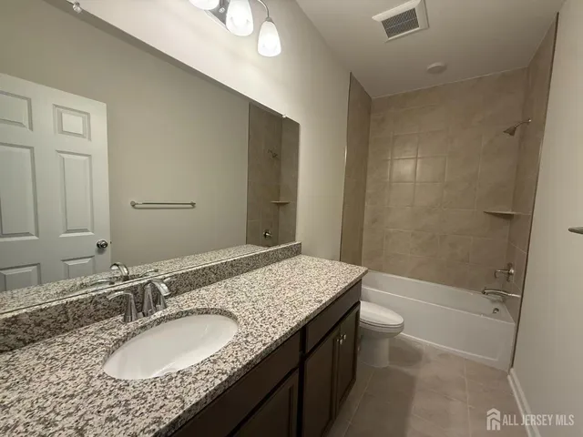 a bathroom with a granite countertop sink a mirror and a bathtub