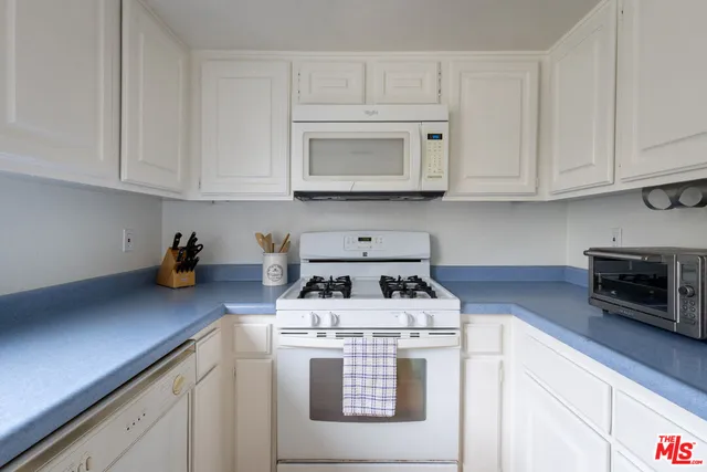 a kitchen with white cabinets and white appliances