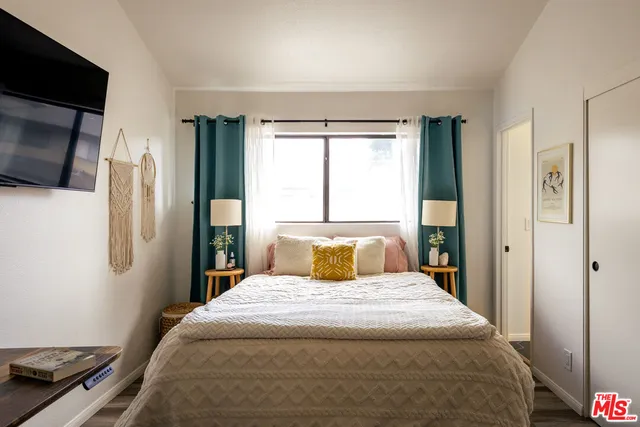 a bedroom with a large bed and a flat tv screen