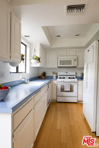 a large white kitchen with stainless steel appliances granite countertop a stove and a sink