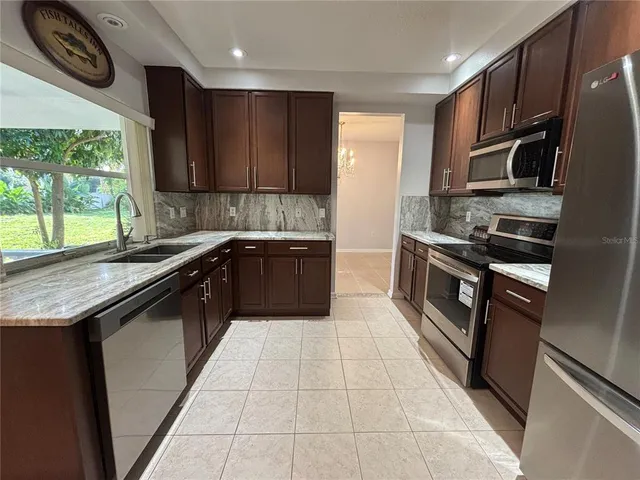 a kitchen with granite countertop a refrigerator stove and sink