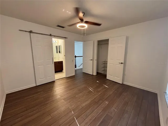 an empty room with wooden floor and a ceiling fan