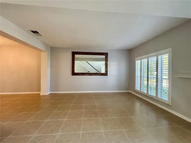 an empty room that has a chandelier fan and windows