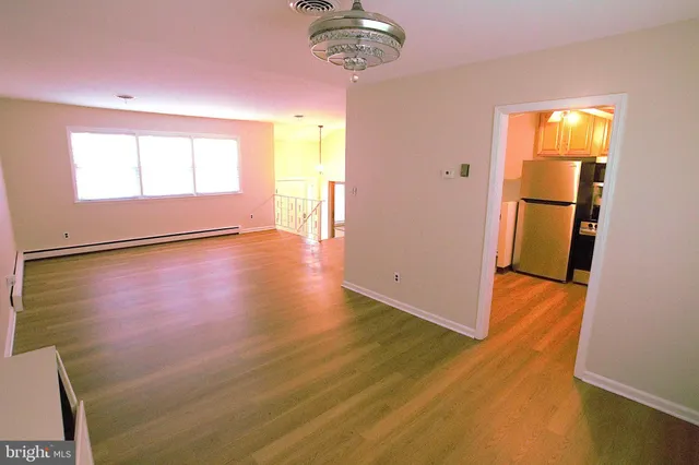 a view of an empty room with a window and wooden floor
