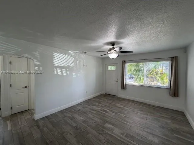 an empty room with wooden floor chandelier fan and windows