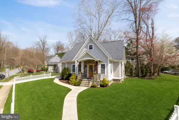a front view of a house with a yard potted plants and large tree