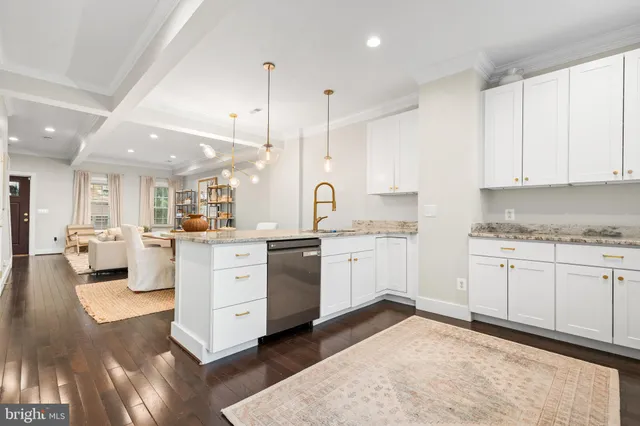 a large white kitchen with a stove a sink dishwasher and a refrigerator with white cabinets