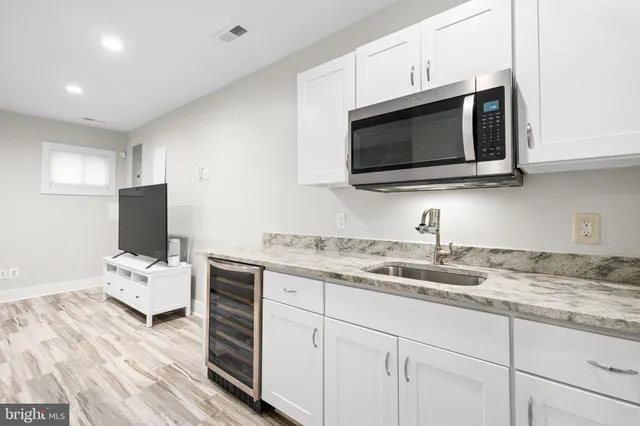 a kitchen with stainless steel appliances granite countertop a sink dishwasher a microwave oven and white cabinets with wooden floor