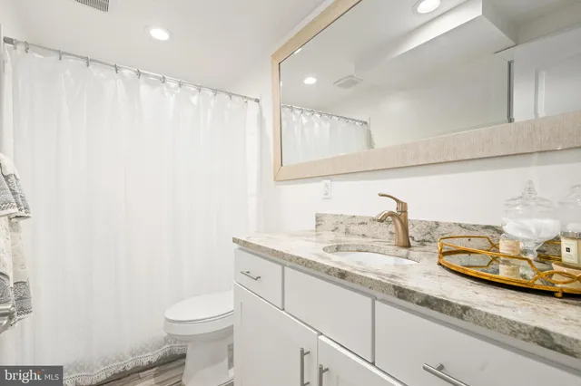 a bathroom with a granite countertop sink a toilet and a mirror