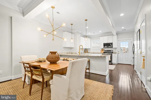 a view of a dining room and livingroom with furniture wooden floor kitchen view and a chandelier