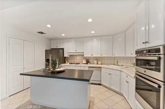 a kitchen with kitchen island a sink dishwasher stove top oven and cabinets