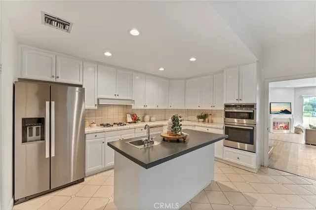 a kitchen with a sink stainless steel appliances and white cabinets