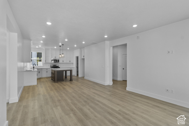 249 West 2920th Street South Logan, UT 84321 - Photo 5 of 23 Wood-finish flooring throughout, recessed lighting, white cabinetry, dark island with integrated seating, and stainless steel appliances