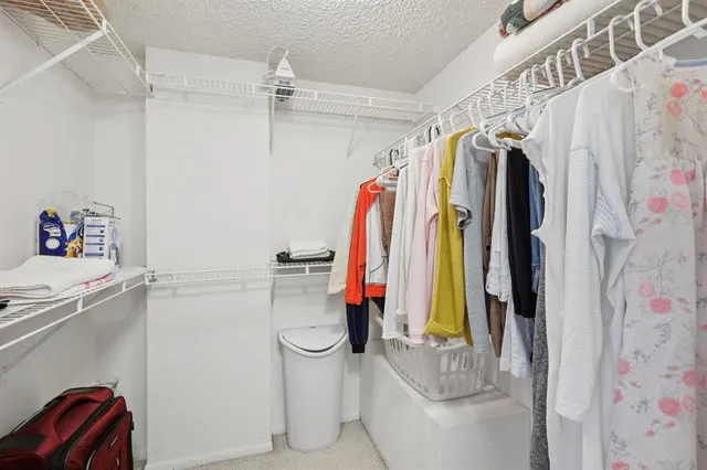 a view of walk in closet with clothes and shoes