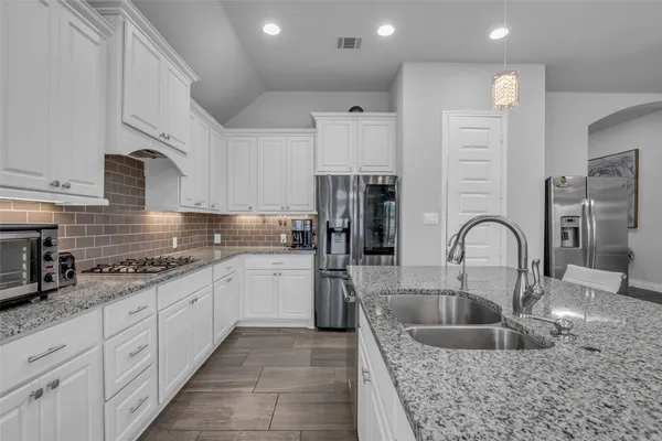 a kitchen with kitchen island granite countertop a sink stainless steel appliances and cabinets