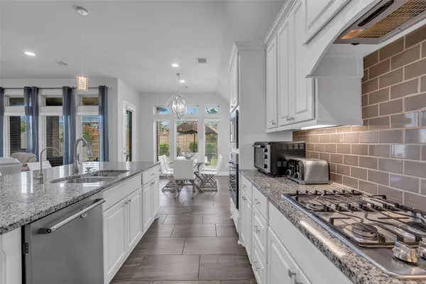 a large kitchen with stainless steel appliances granite countertop a lot of counter space a sink and a stove