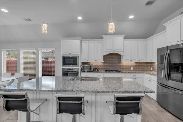 a kitchen with stainless steel appliances granite countertop a stove refrigerator sink and cabinets