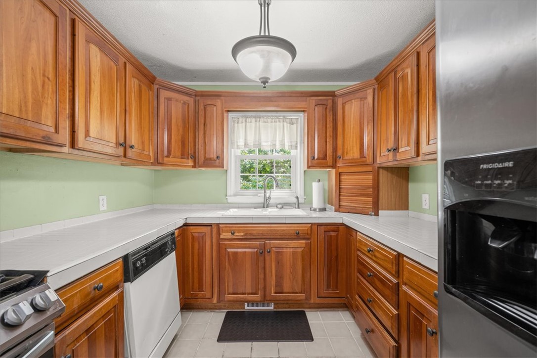 668 Marcengill Road Westminster, SC 29693 - Photo 13 of 37 Well-appointed kitchen featuring abundant wood cabinetry and tiled countertops with a garden window.