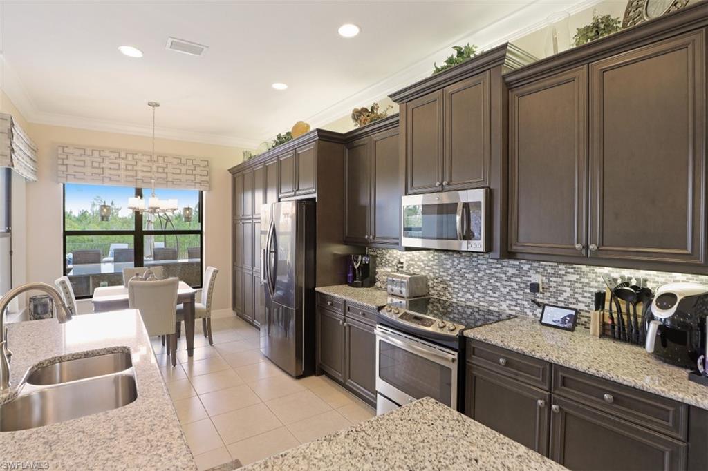 2832 Cinnamon Bay Circle Naples, FL 34119 - Photo 11 of 35 a kitchen with stainless steel appliances granite countertop a sink stove and refrigerator