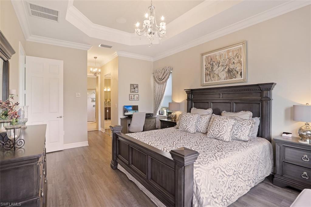 2832 Cinnamon Bay Circle Naples, FL 34119 - Photo 17 of 35 a bedroom with a large bed and a chandelier
