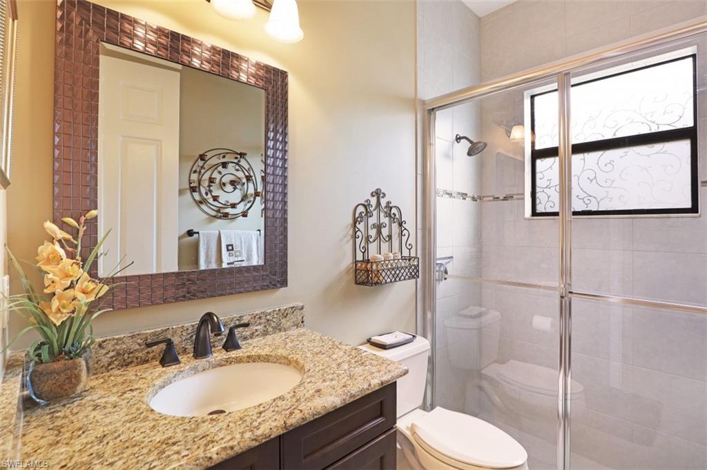 2832 Cinnamon Bay Circle Naples, FL 34119 - Photo 19 of 35 a bathroom with a granite countertop toilet sink and mirror