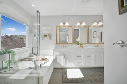 a bathroom with a double vanity sink mirror and bathtub