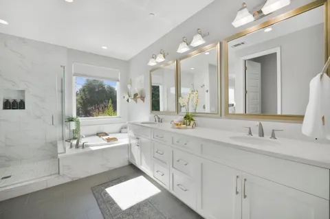 a spacious bathroom with a double vanity sink a mirror and a bathtub