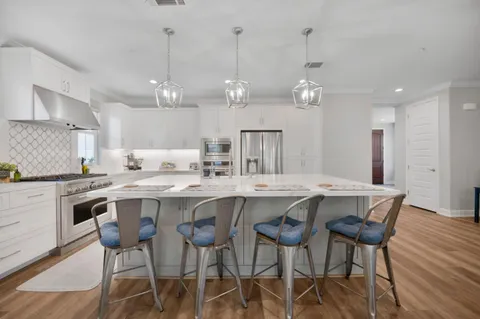 a kitchen with a dining table chairs stainless steel appliances and cabinets